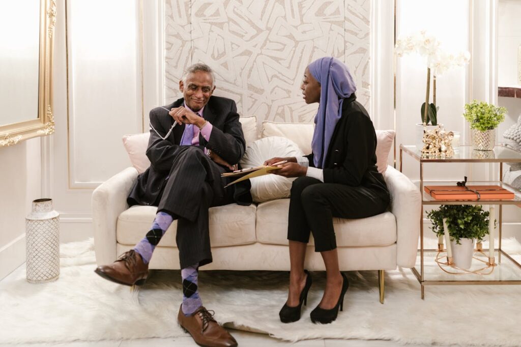 A man and woman engage in professional discussion in an elegant indoor setting, highlighting diversity.